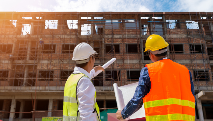Dos profesionales con cascos revisan la construcción de un edificio, reflejando la adaptación de infraestructuras ante los Cambios Climáticos en Argentina.