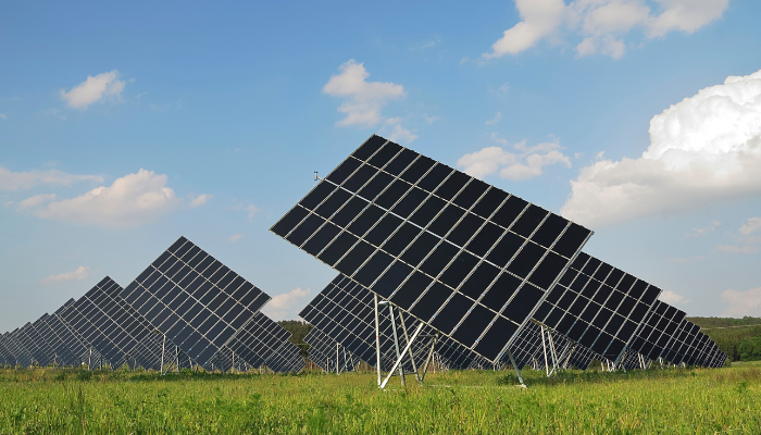 Rows of adjustable solar panels in a grassy field, illustrating a commitment to clean energy innovation.