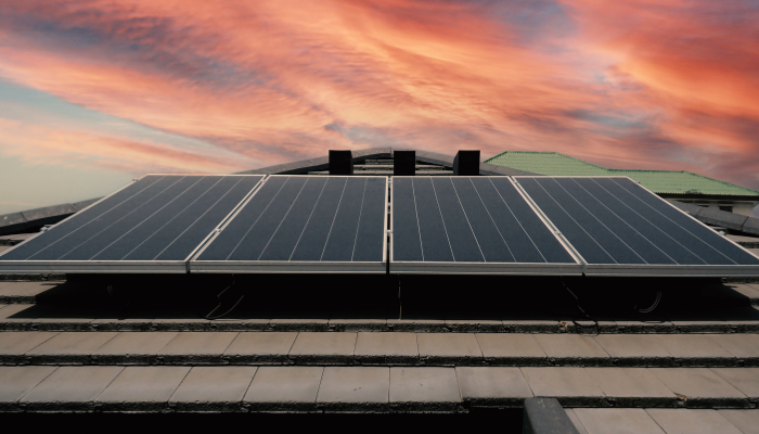 Un conjunto de paneles solares en el techo se recorta contra un cielo colorido, ejemplificando la adopción de energías renovables dentro de la Distribución Eléctrica en Argentina.