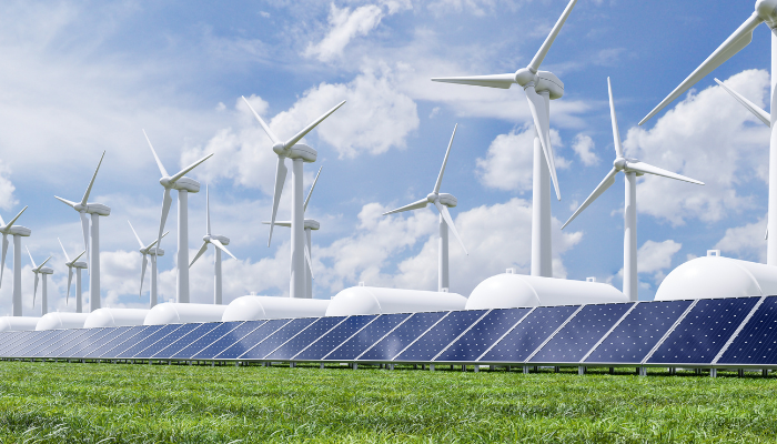 Conjunto de turbinas eólicas y paneles solares sobre un prado