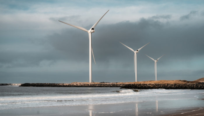 Tres aerogeneradores se alzan cerca de la costa, reflejando la creciente adopción de las Energías Renovables en Argentina.