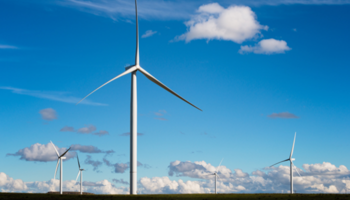 Large wind turbines standing under a bright blue sky, highlighting the growth of Energy Projects in UK.