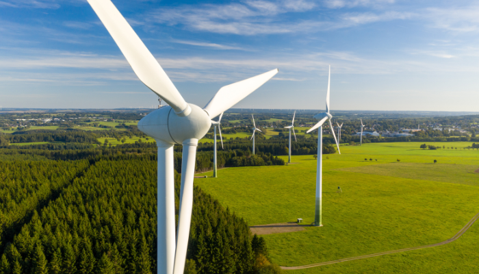 Several wind turbines stand tall in a vast green field, showcasing the growth and innovation of Energy Projects in US focused on renewable energy.