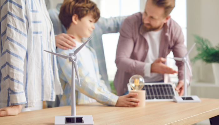 Una familia observa maquetas de turbinas eólicas y un panel solar, reflejando la concientización