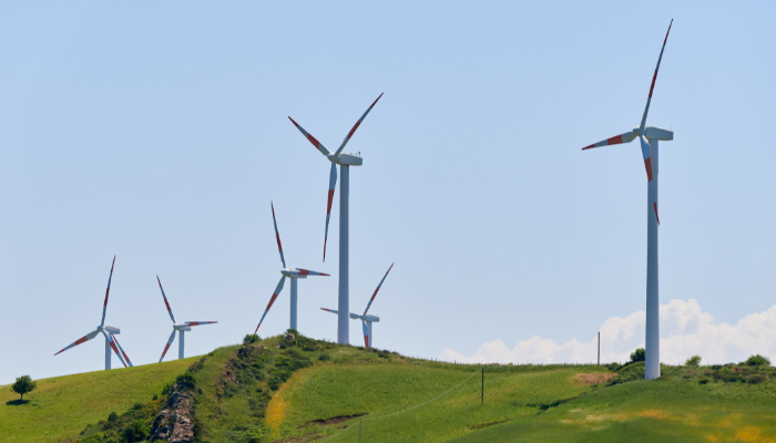 Varios aerogeneradores se alzan sobre colinas verdes, simbolizando el crecimiento