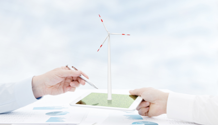 Two professionals hold a tablet displaying a model wind turbine, highlighting cutting-edge strategies for Sustainability in the UK.