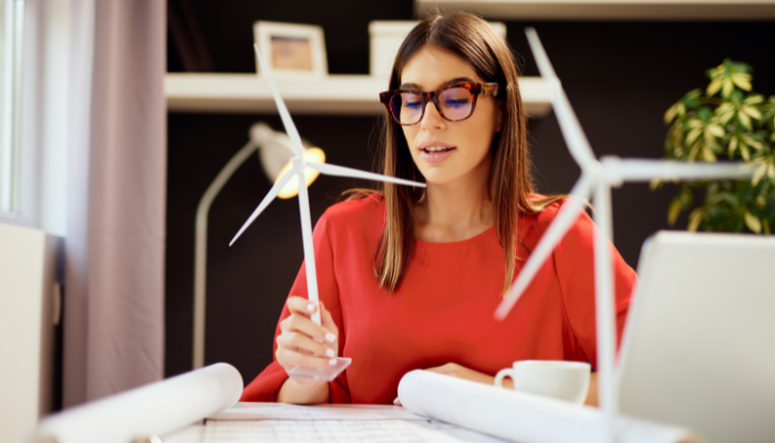 Una profesional analiza una maqueta de turbina eólica sobre su escritorio