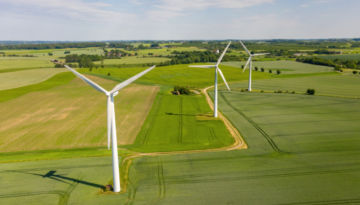 An aerial view of wind turbines surrounded by green fields, symbolizing sustainable energy solutions.