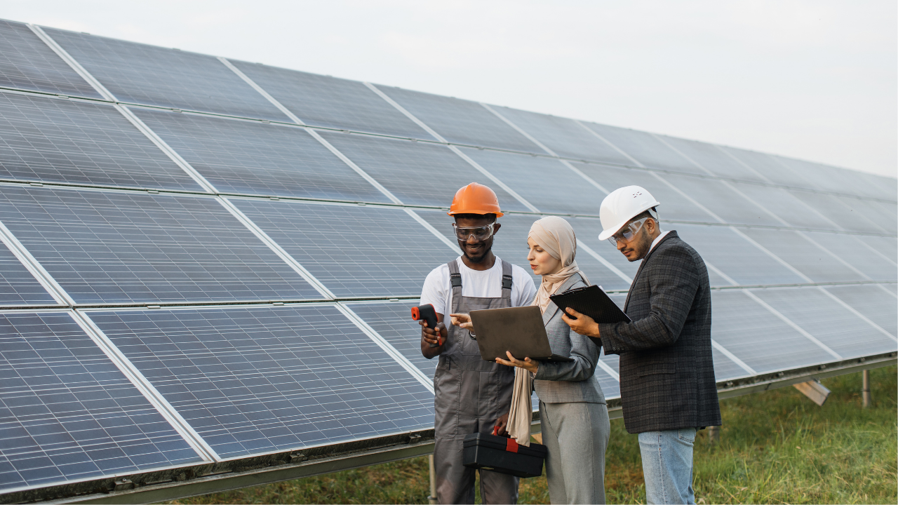 Three professionals in safety gear examine solar panels in an open field. The phrase "Solar panels" aligns with the technological and collaborative context, suggesting an inspection or evaluation of the system.