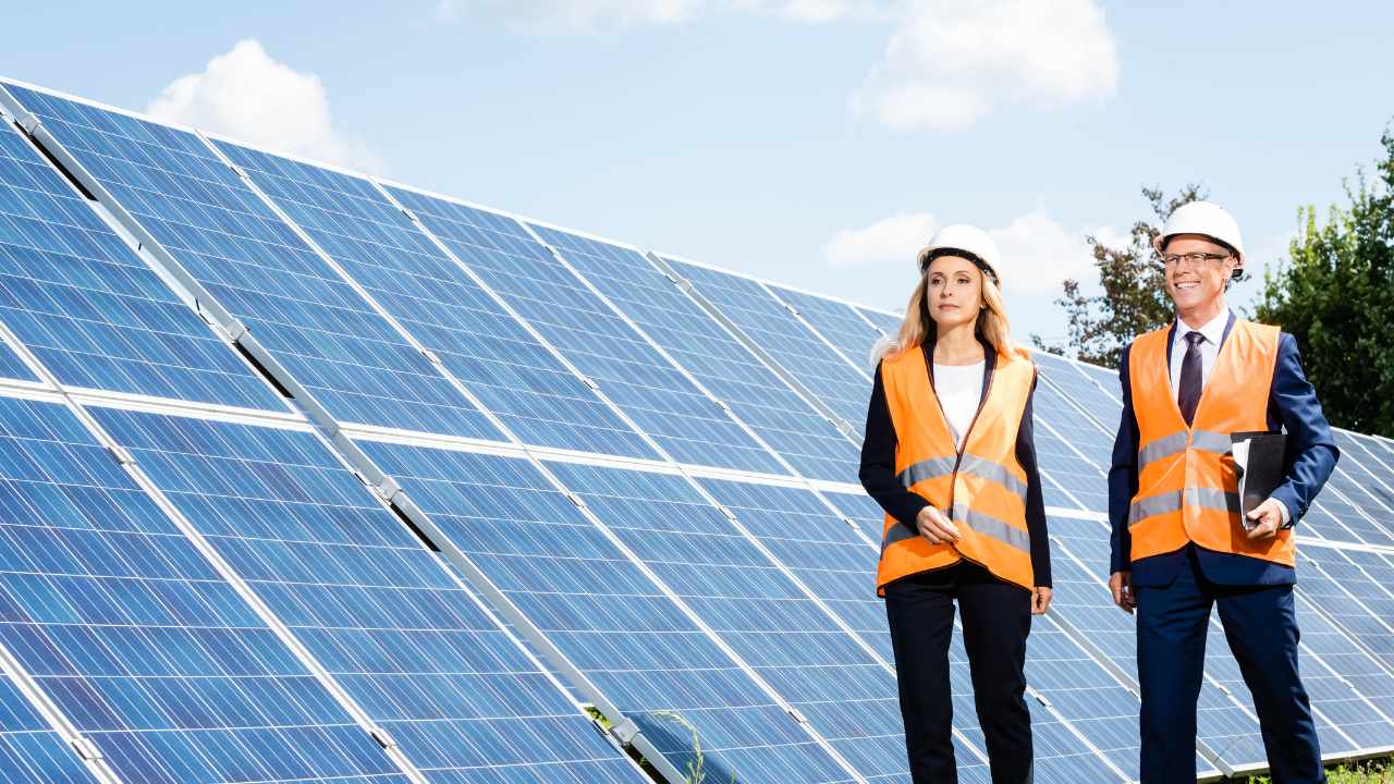 Dos profesionales con chalecos reflectantes caminan junto a una instalación solar. La frase "Paneles solares" se integra con naturalidad en esta escena de supervisión técnica en exteriores.