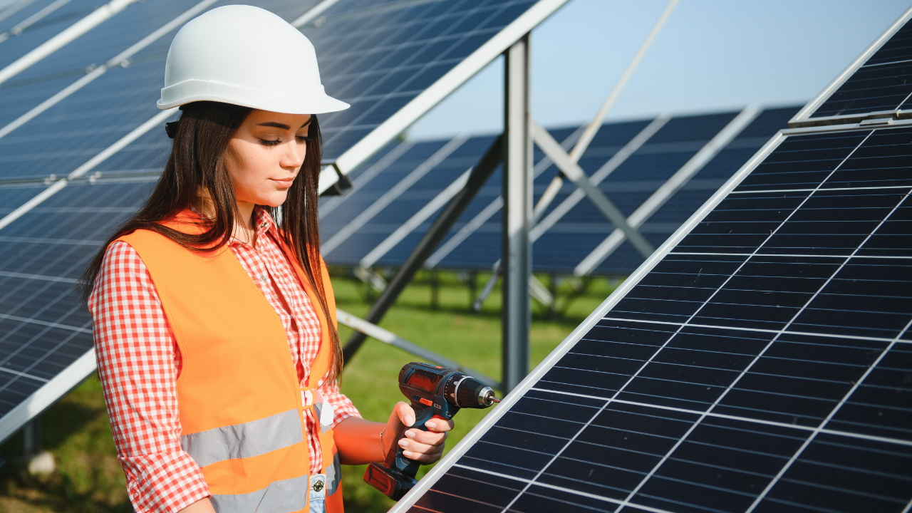 Una joven trabajadora con casco y taladro inspecciona un panel solar, simbolizando la participación activa y creciente de nuevas generaciones en el desarrollo de la energía solar hogar en Uruguay.