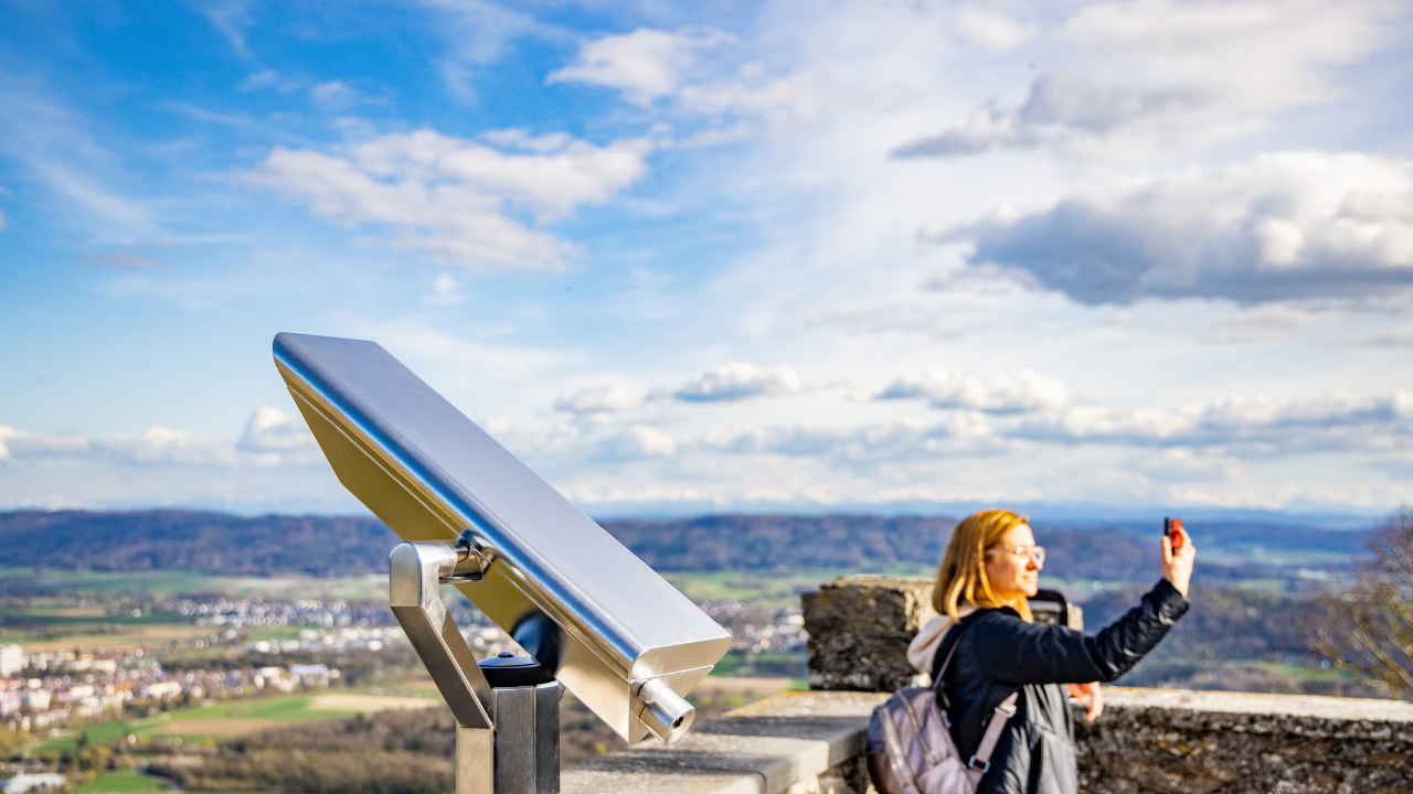 Una turista toma una fotografía mientras observa un mirador equipado con panel solar. La integración del panel en un espacio público ilustra una forma moderna y accesible de autoconsumo compartido desde una perspectiva comunitaria.