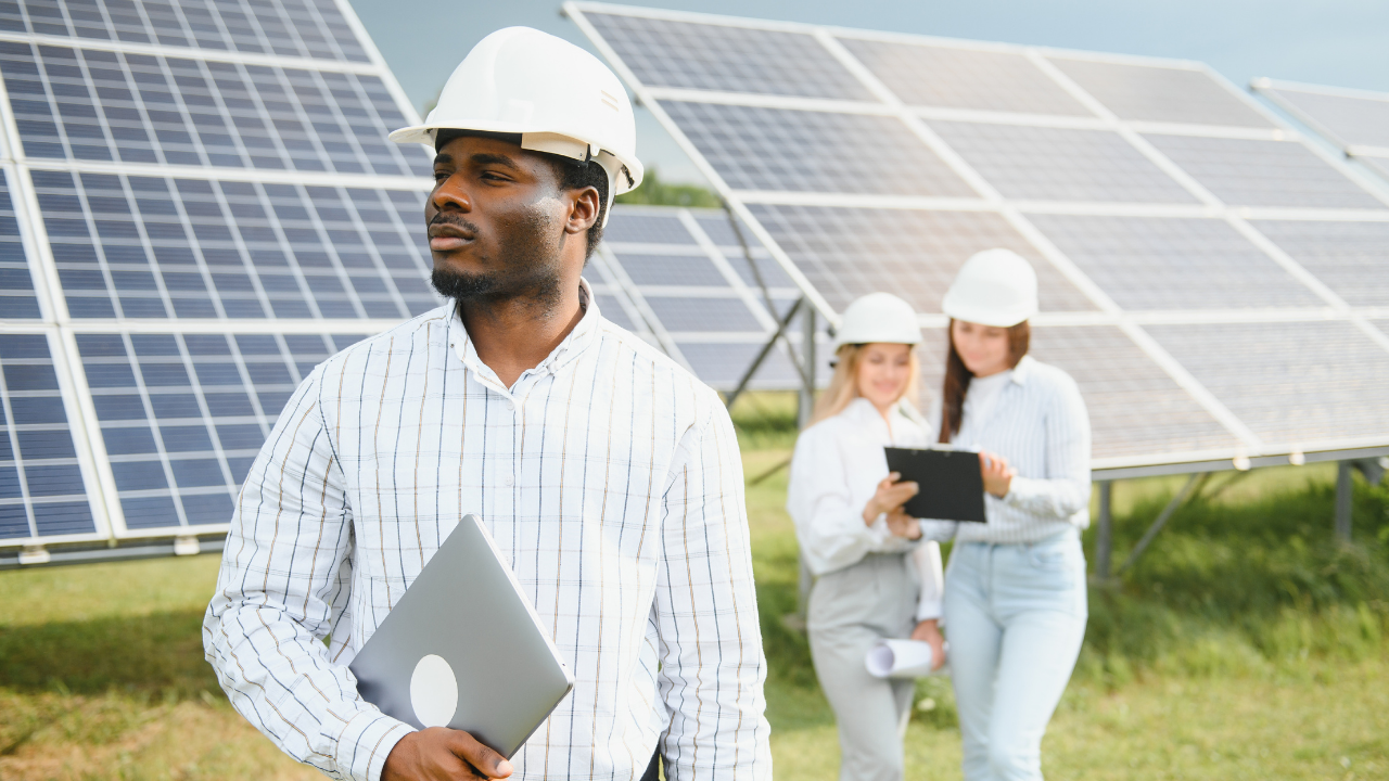 A professional stands confidently near solar panels, while two colleagues work in the background. The composition emphasizes architectural integration by showcasing how clean energy infrastructure can coexist within a functional and aesthetically planned environment.