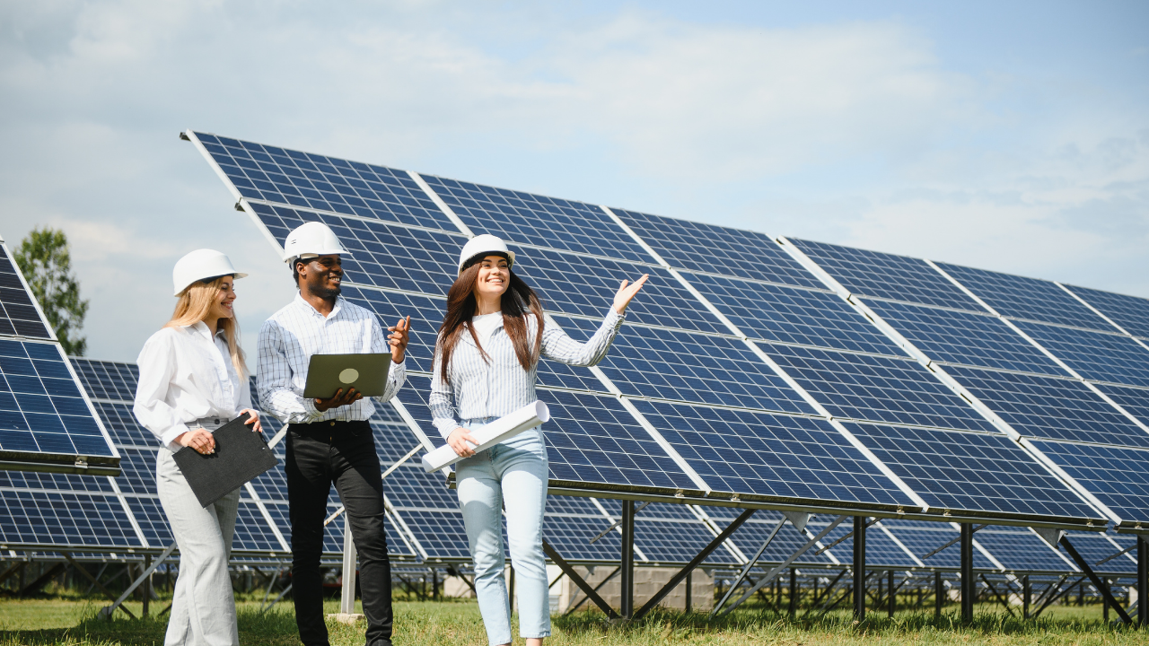 Three engineers walk through a solar installation, smiling and exchanging ideas. The open field of panels represents the widespread use of photovoltaic technology while inviting reflection on its differences from thermal systems.