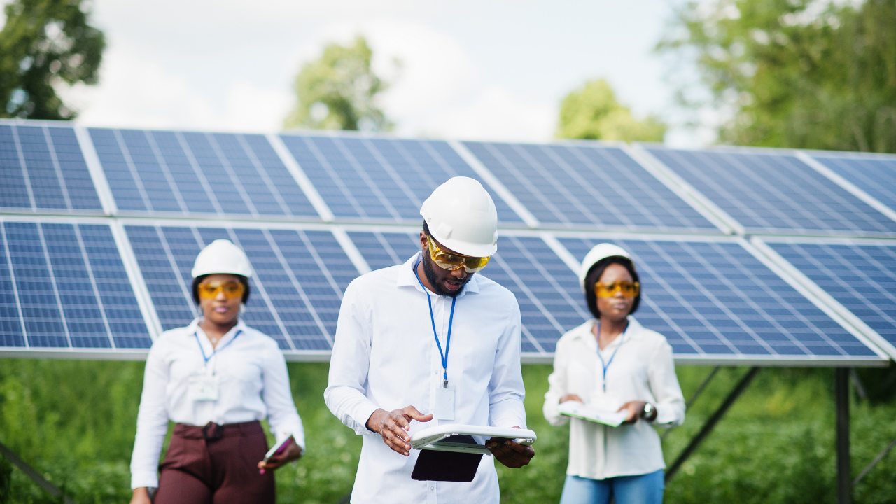 Tres técnicos revisan documentación mientras caminan entre los paneles solares, simbolizando la planificación y ejecución del mantenimiento de paneles solares.
