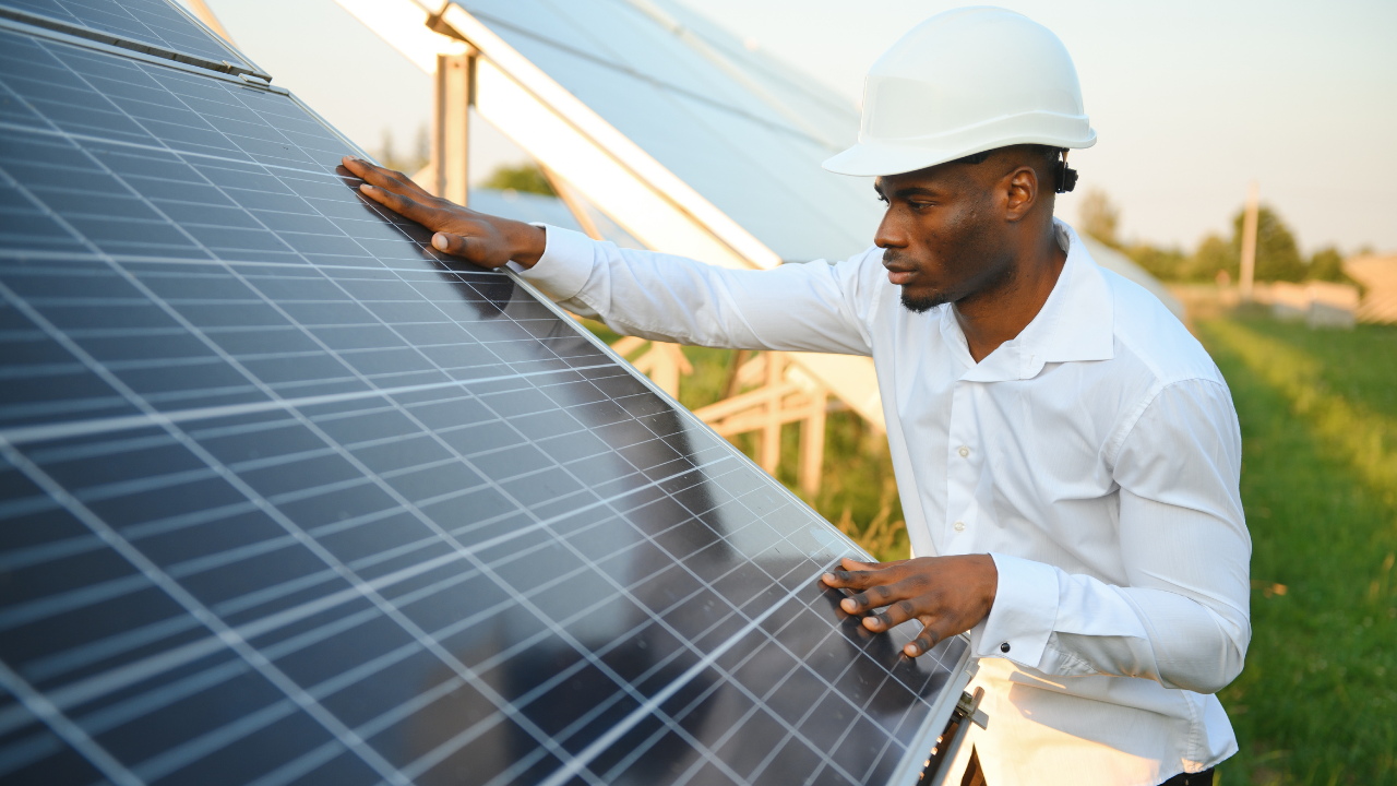 Un técnico revisa cuidadosamente un panel solar en un entorno rural, simbolizando la conexión entre tecnología y sostenibilidad. Su acción destaca la importancia de instalar paneles solares en casa.