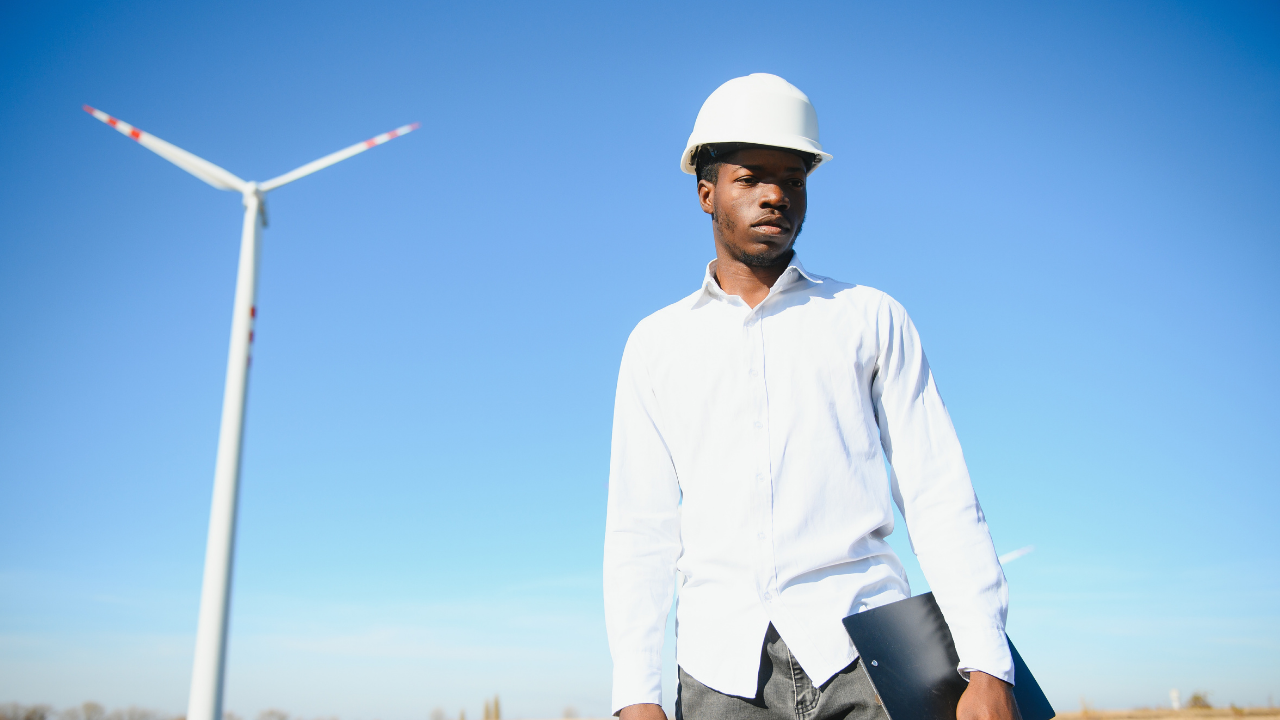 Un ingeniero español con casco blanco observa el entorno con determinación, representando el liderazgo técnico del país en proyectos de aerogeneradores sin aspas.