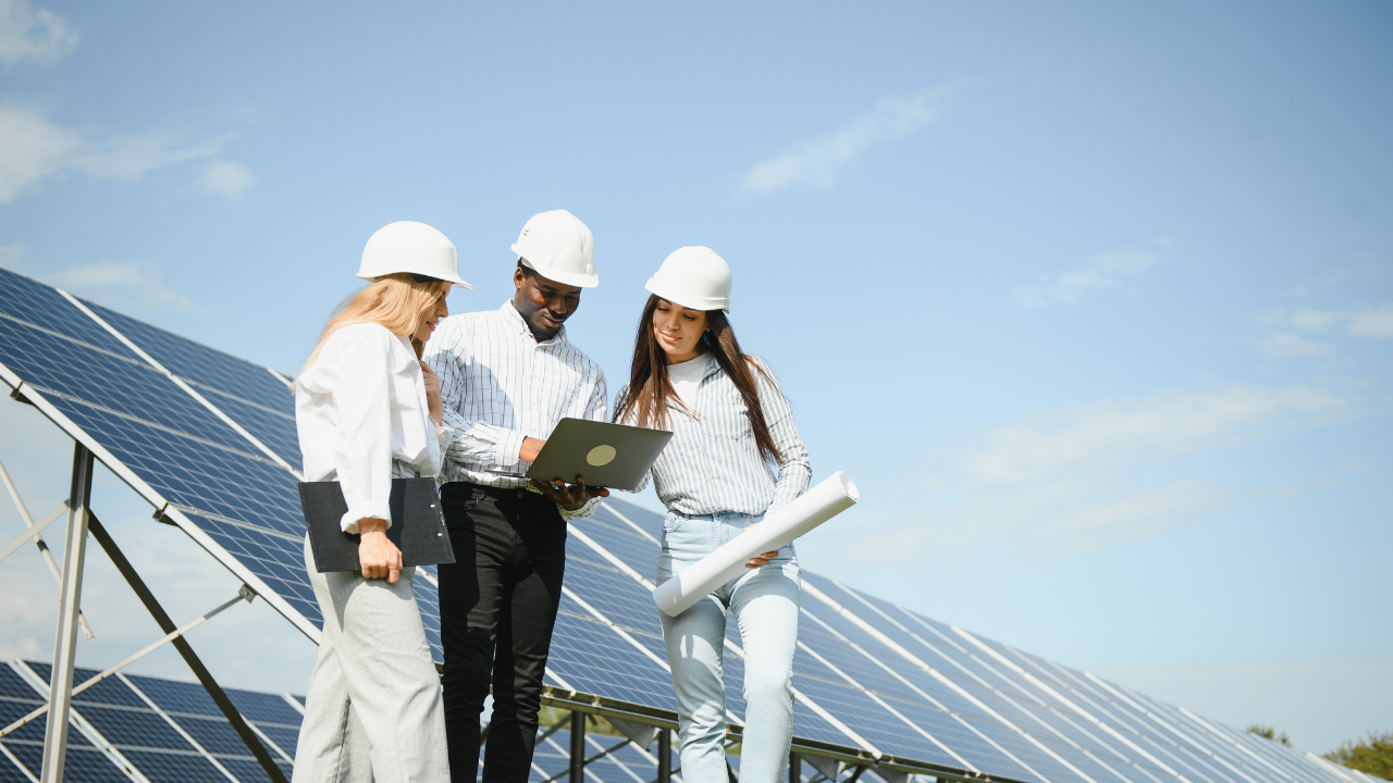Tres profesionales revisan información técnica frente a los paneles solares, reflejando planificación y avance en la infraestructura energética de Argentina.