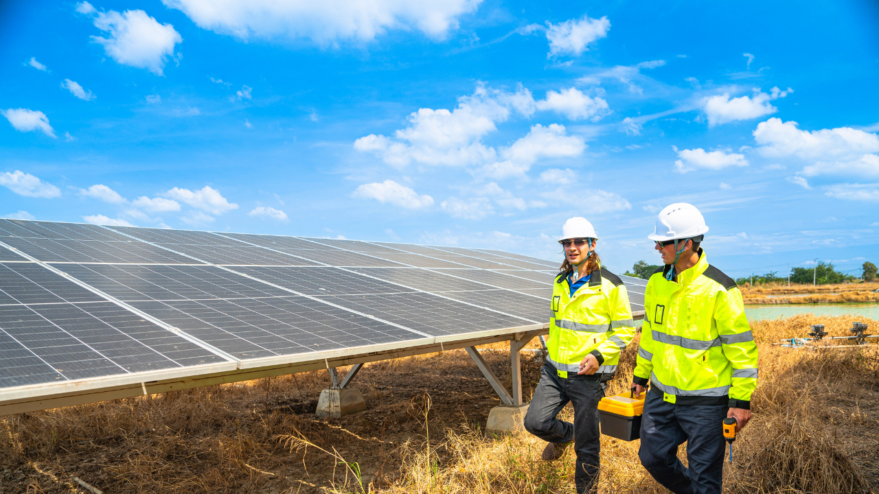 Dos técnicos caminan junto a una instalación de paneles solares bajo un cielo despejado, mostrando el compromiso español con la sostenibilidad y el entorno rural.