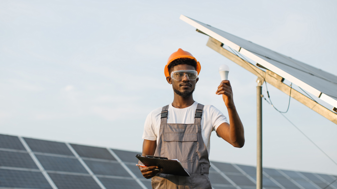 A technician holding a clipboard and an LED bulb inspects solar panels, visually linking energy efficiency with a strong return on investment in sustainable infrastructure.