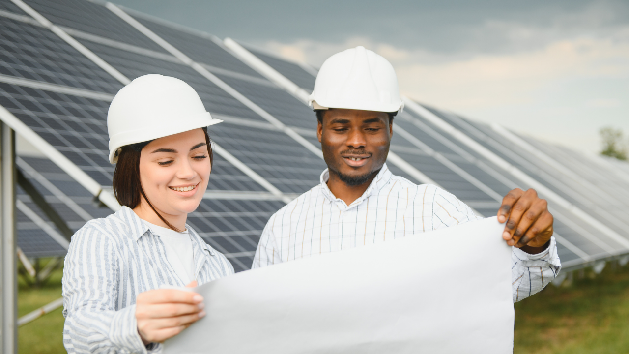Dos profesionales revisan planos con satisfacción frente a una instalación solar, reflejando los frutos del esfuerzo y el positivo retorno de inversión en tecnología limpia.