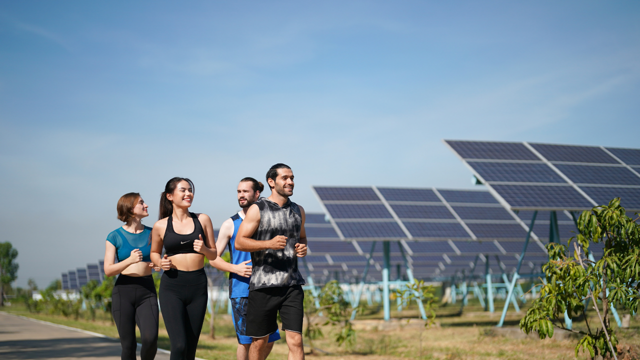 Un grupo de jóvenes corre junto a paneles solares, transmitiendo vitalidad y bienestar como símbolo del impacto social y ambiental del retorno de inversión en energías limpias.