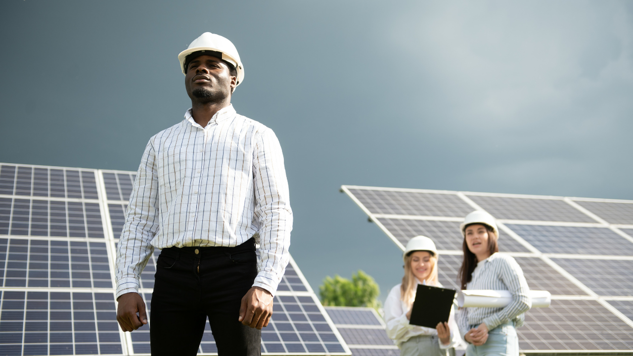 Tres profesionales, dos mujeres con planos y un hombre al frente, supervisan un parque solar. La imagen, con un cielo nublado de fondo, refleja el creciente liderazgo técnico en España en la reutilización de paneles solares usados, subrayando innovación y equidad de género en el sector.