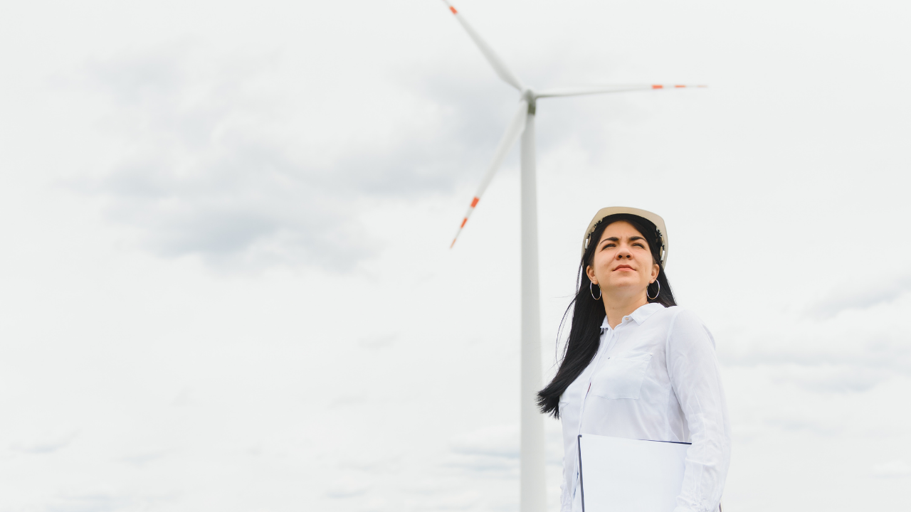 Una ingeniera uruguaya observa el entorno con determinación frente a un aerogenerador, reflejando el papel clave del país en la adopción de energía eólica.