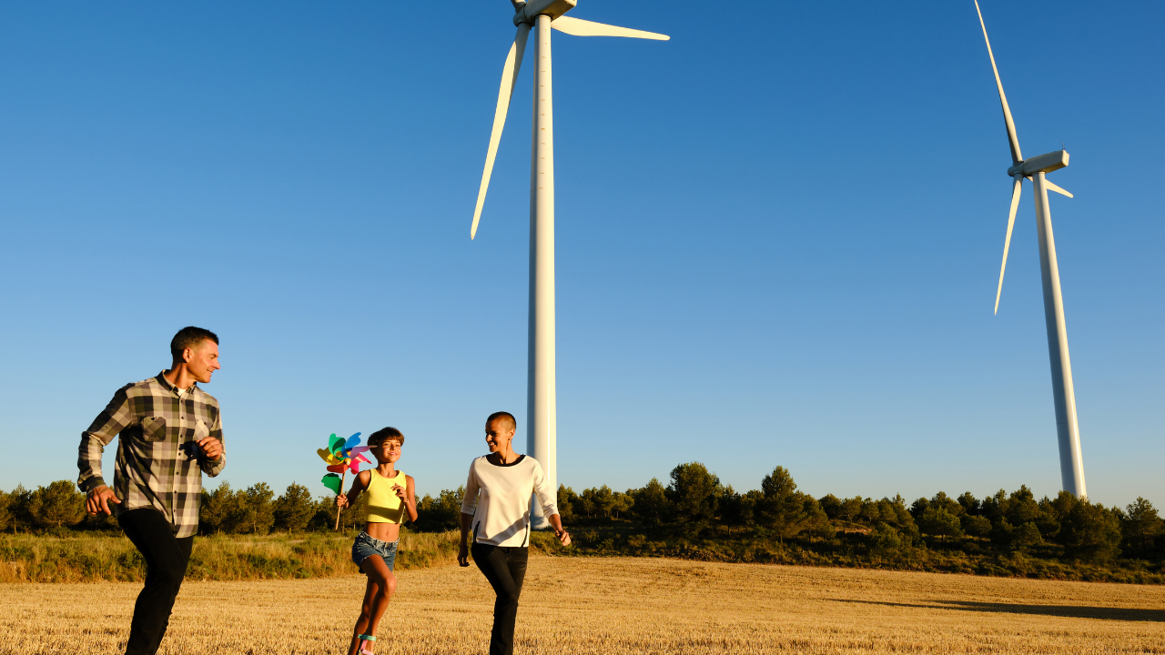 A family enjoys outdoor time near wind turbines, symbolizing the connection between home wind energy and sustainable living.