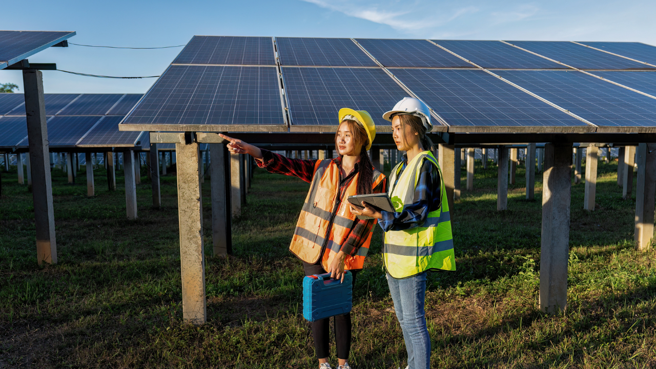 Dos técnicas inspeccionan una planta solar en el campo, vestidas con ropa de seguridad y cascos. Una de ellas señala hacia el horizonte mientras la otra consulta una tablet. El mensaje visual promueve la innovación energética bajo el concepto de Energía solar de concentración.