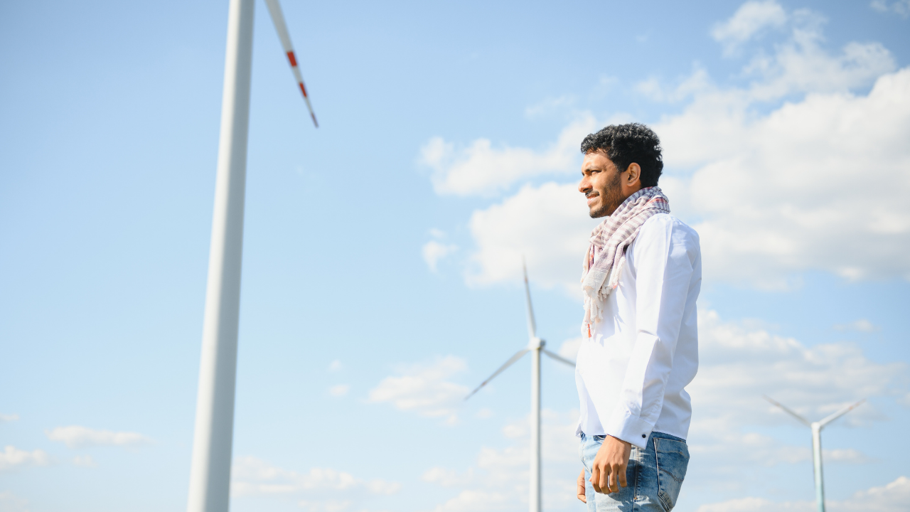 A man stands proudly among wind turbines, his expression reflecting optimism and support for wind energy.