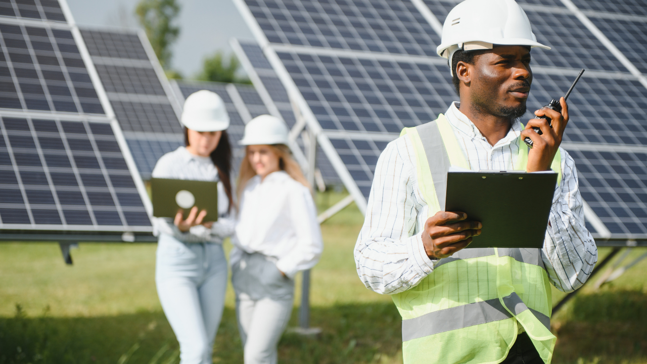 A technician with a safety vest and walkie-talkie coordinates field operations while two colleagues work on laptops near the solar arrays. "Clean solar panels" highlights the technical and organized approach to renewable energy maintenance.