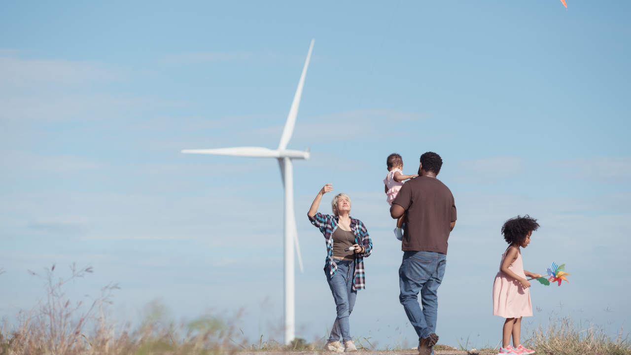 A family enjoys outdoor activities near a wind turbine, reflecting how renewable energy spaces can support family well-being and inclusive leisure.