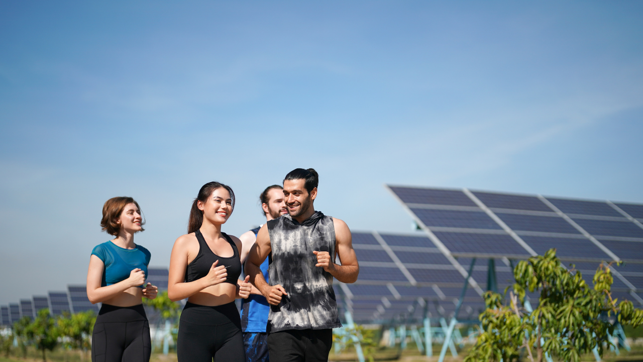 Un grupo de jóvenes trota al aire libre junto a una instalación solar. La frase "limpiar paneles solares" se integra como un mensaje simbólico de armonía entre vida saludable y conciencia ecológica en espacios comunitarios.