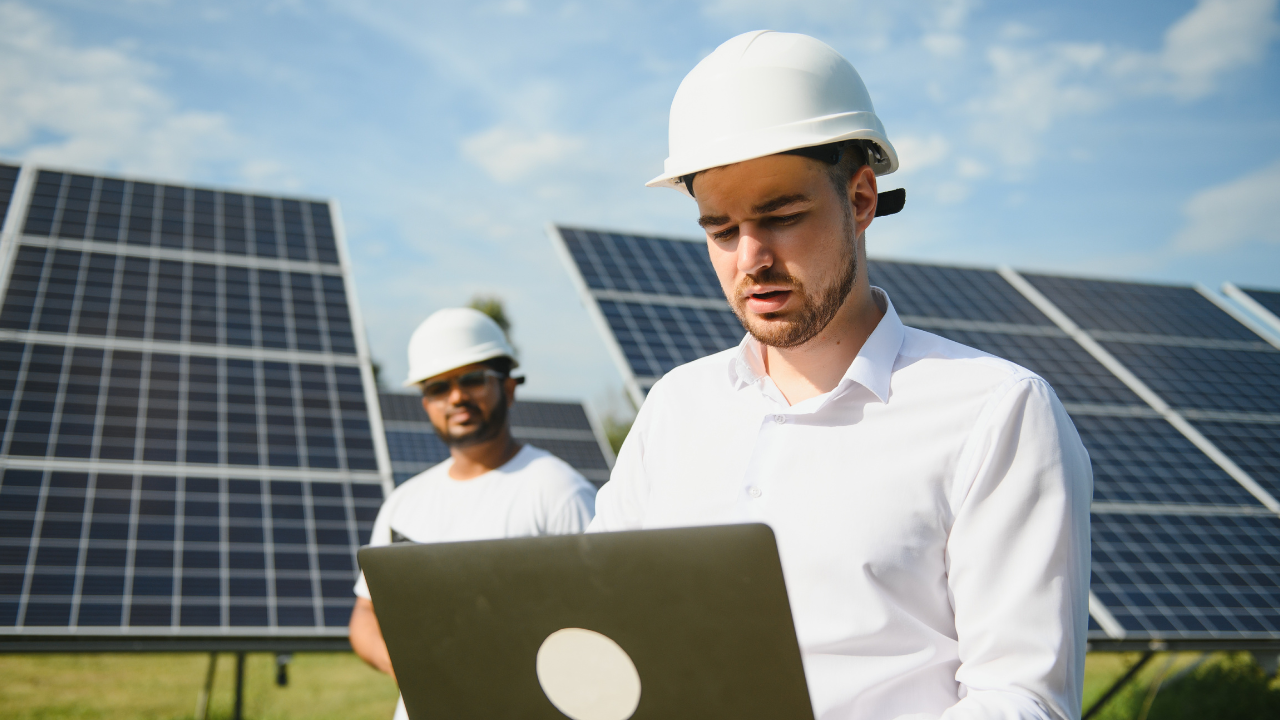 Técnicos revisan información en un ordenador portátil entre paneles solares, destacando el enfoque analítico y profesional hacia la energía solar hogar en España.