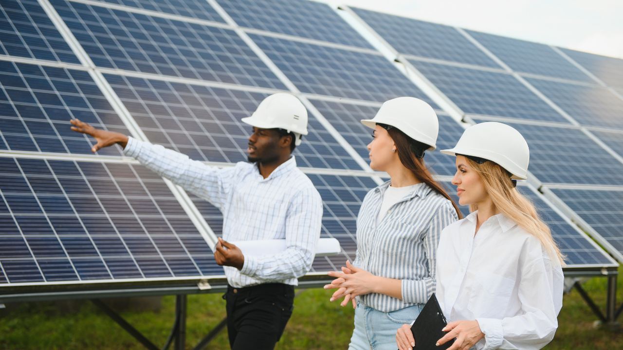 Un ingeniero señala hacia la instalación mientras conversa con sus colegas. La frase "instalación solar aislada" refleja el enfoque educativo y estratégico en el uso de energías renovables fuera de la red convencional.