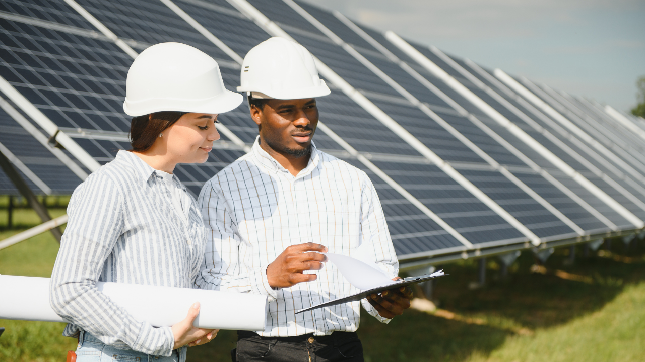 En una jornada soleada, dos técnicos revisan planos frente a paneles solares, reflejando el compromiso local con la energía solar y el trabajo en equipo.