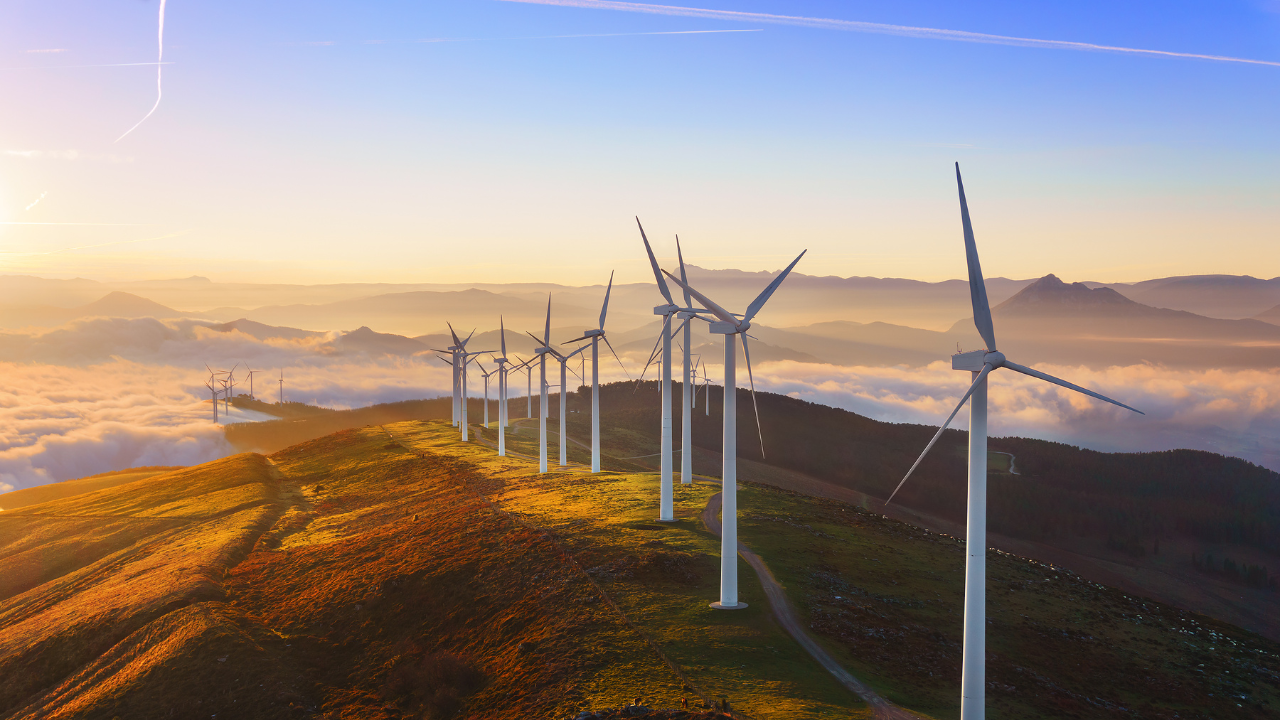 In a serene mountainous landscape at sunrise, a line of wind turbines harnesses natural energy, symbolizing the eco-conscious shift toward the home wind turbine movement.