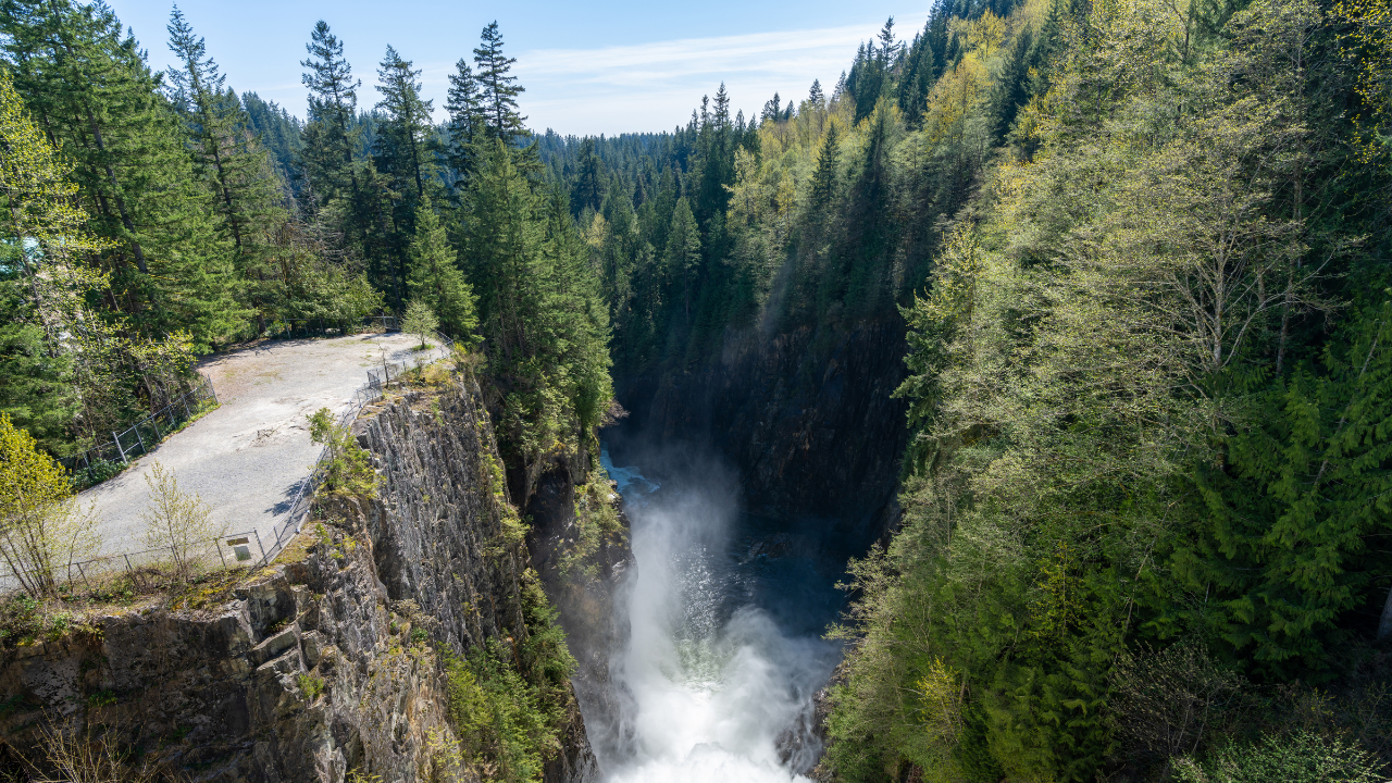 Nestled within a forested gorge, a powerful waterfall suggests hidden geothermal energy potential deep beneath the lush terrain.
