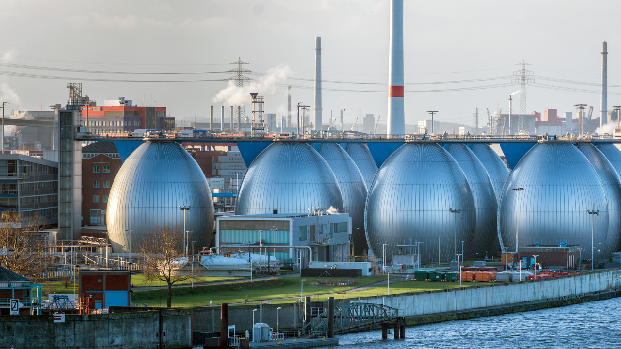 Una planta industrial moderna junto al agua sugiere la implementación tecnológica necesaria para convertir la energía undimotriz en electricidad sostenible.