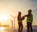 American workers on a solar farm discuss data related to wind and solar synergy, representing a practical application of aerothermal energy.