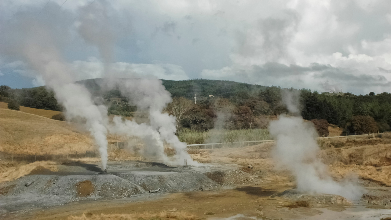 Una serie de respiraderos naturales de vapor en un campo abierto muestra cómo la Geotermia en el hogar puede surgir de fuentes geotérmicas naturales sin infraestructura invasiva.