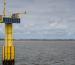 Una torre amarilla con paneles solares cerca del mar simboliza el monitoreo costero y su posible vínculo con la energía mareomotriz.