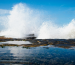 Ocean spray crashes dramatically against rocks, symbolizing the untapped force of wave energy available on the American shoreline.