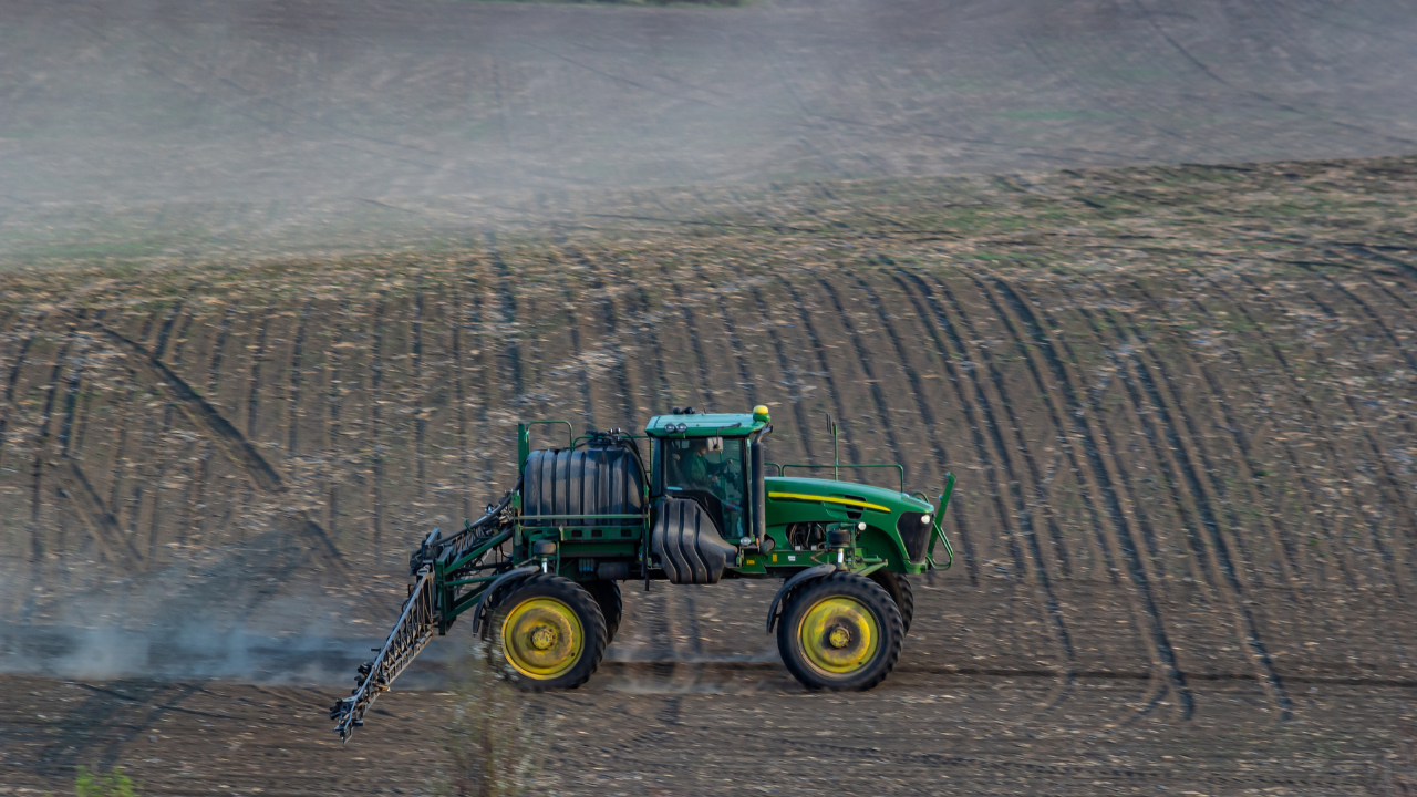 Un tractor equipado con aspersores trabaja sobre un campo arado, mostrando cómo la Aerotermia puede integrarse a la agricultura de precisión.