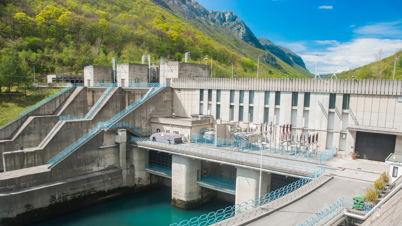 La estructura moderna de concreto y las barandillas azules destacan el diseño funcional y seguro de las centrales hidroeléctricas en zonas montañosas.