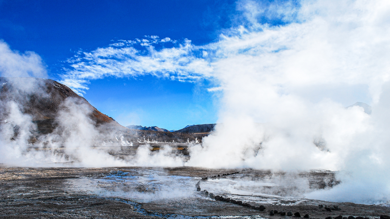Campos geotérmicos emanan columnas de vapor entre montañas, resaltando el uso natural y directo de la energía geotérmica en el entorno.