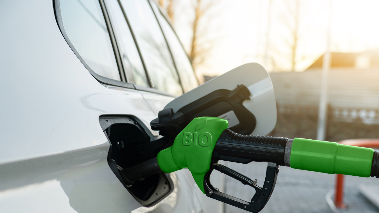Una manguera verde conectada al tanque de un coche moderno resalta el uso práctico y presente de los biocombustibles en la movilidad cotidiana.